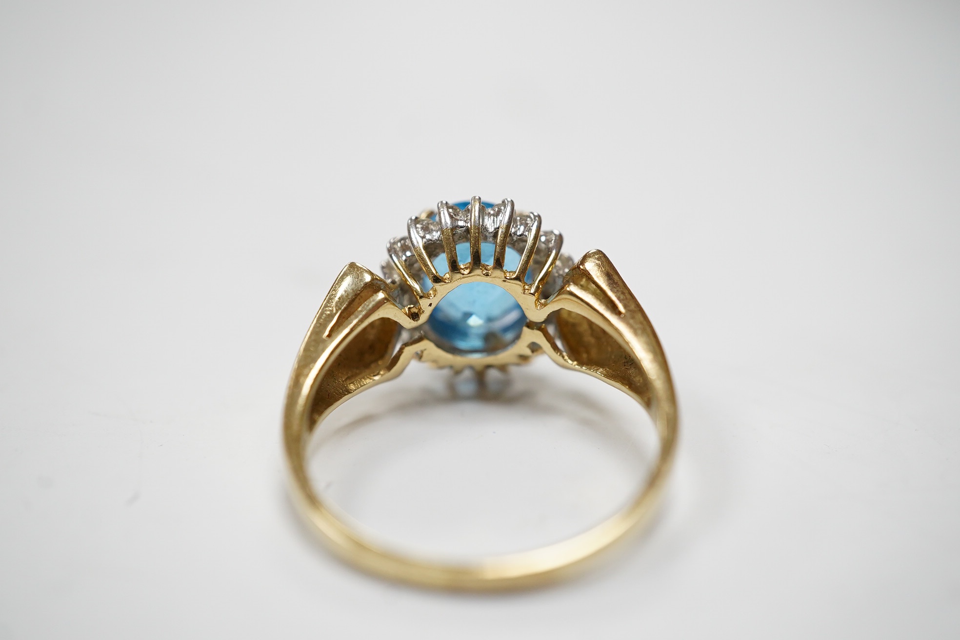 A modern 14k and oval cut blue topaz set dress ring, bordered with diamonds, size R, gross weight 4.7 grams. Condition - fair to good.